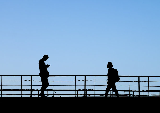 两个人从人行桥上走向对方的剪影图片下载