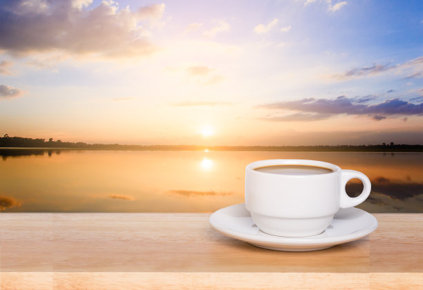 木桌上的白色咖啡杯和落日的景色图片下载