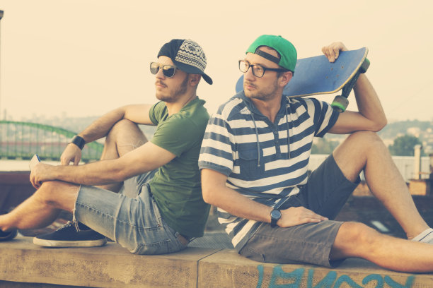 两个年轻人坐在墙上。图片下载