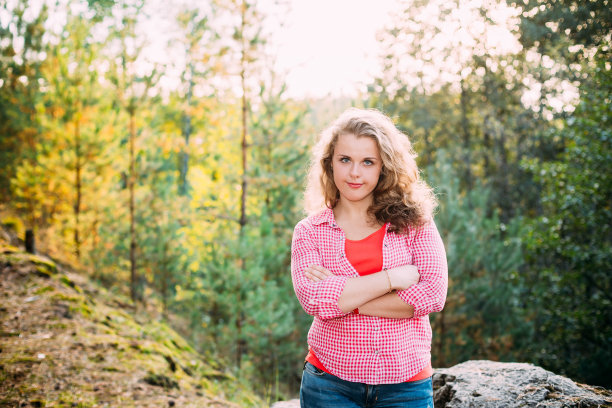 美丽的加大尺寸的年轻女子在衬衫摆姿势在森林图片下载