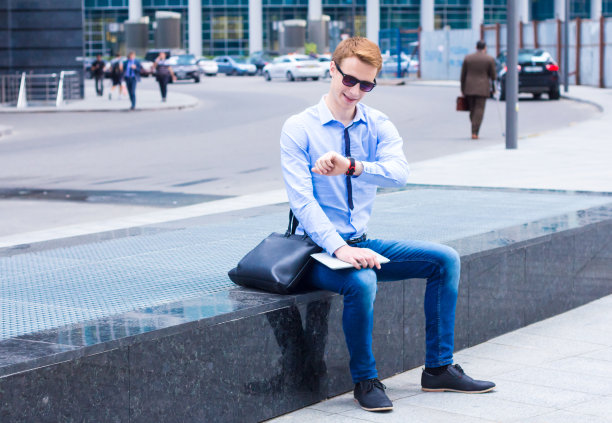 年轻的商人看着街上的钟图片下载