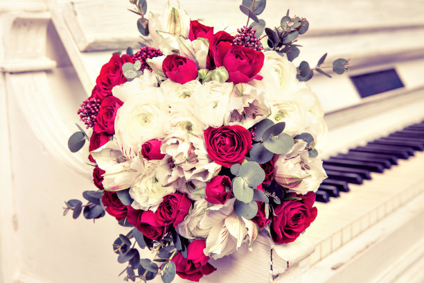 新娘的玫瑰花束放在钢琴琴键上。图片下载