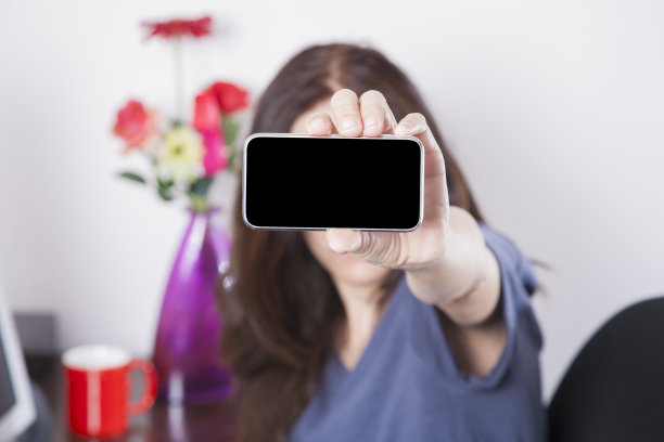 身穿蓝色衬衫的女士正在展示屏幕智能手机图片下载