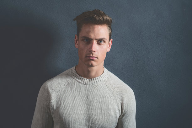 时尚休闲的年轻人穿着米色毛衣。图片下载