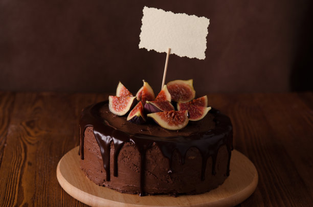 巧克力蛋糕配无花果，奶油和糖霜在棕色的木头上图片下载