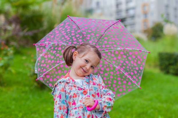 带着伞微笑的可爱小女孩在公园里图片下载
