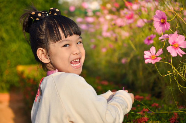 小女孩在花园里玩花。图片下载