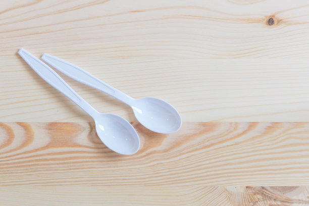 天然木材背景上的塑料汤匙图片下载