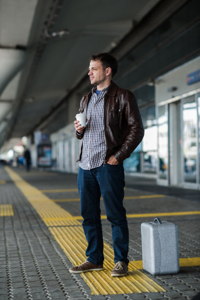 年轻的普通人拿着杯子站在机场附近等着图片下载