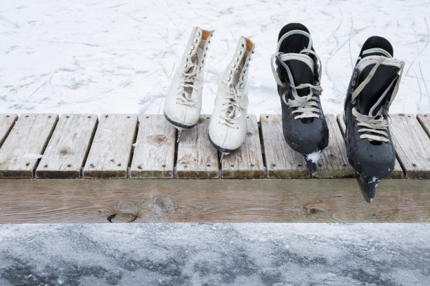 旧的黑白冰鞋放在木凳上。图片下载