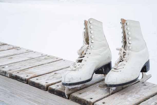 旧的白色冰鞋在冰区的木凳上。图片下载