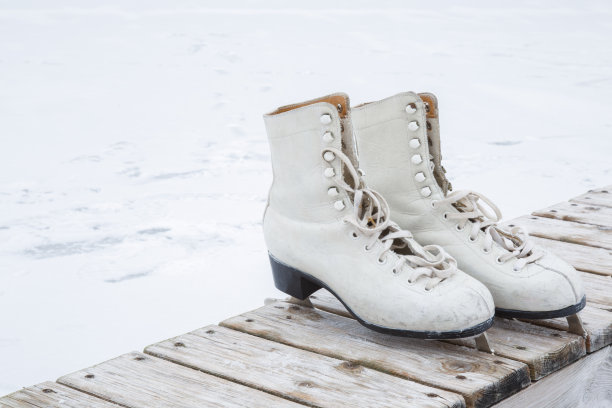 旧的白色冰鞋在冰区的木凳上。图片下载
