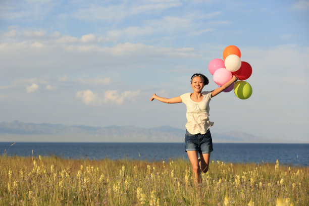 在草地上用彩色气球欢呼的年轻女子图片下载