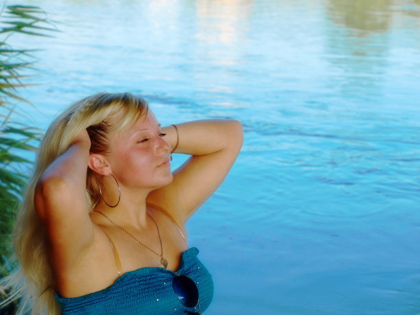 年轻的梦幻女孩在蓝色的河边。图片下载