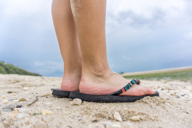 穿着凉鞋站在沙滩上的女孩图片下载