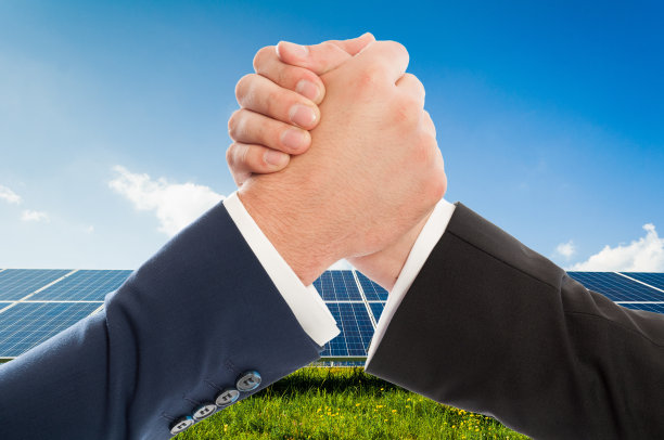 在太阳能光伏板上，商人们像团队合作一样握手图片下载
