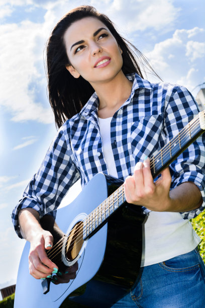 女孩在绿色的草地上弹吉他图片下载