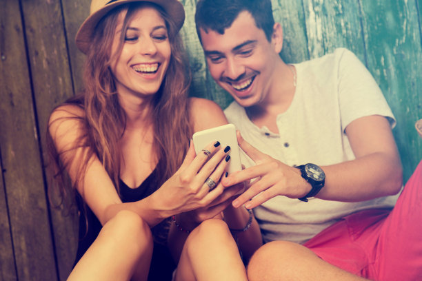 情侣在户外用手机相爱。图片下载