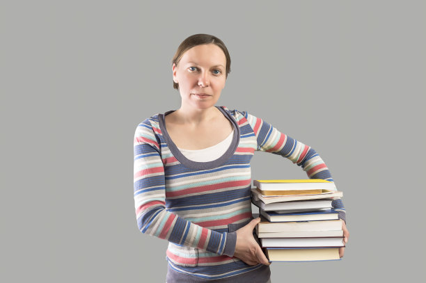 拿着一堆书的学生。图片下载