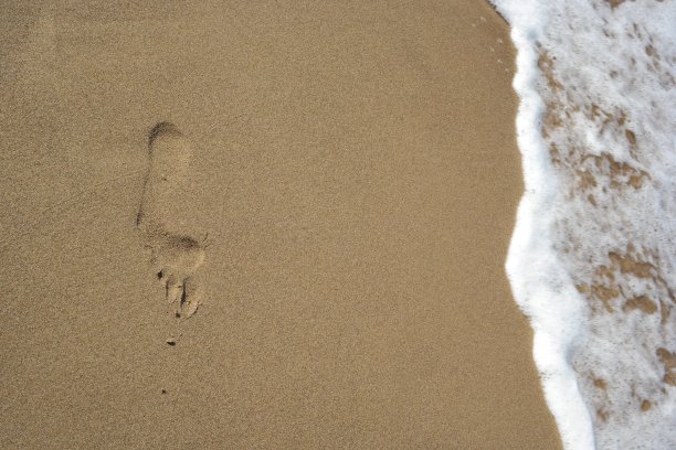 一脚踩在沙滩上，海面波涛汹涌图片下载