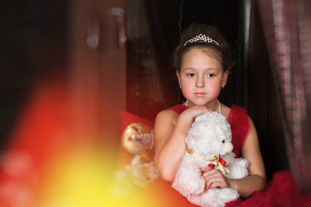 穿着红色连衣裙的体贴女孩抱着一只毛绒熊图片下载