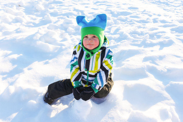 小孩子在冬天坐在外面的雪地上图片下载