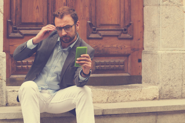 年轻英俊的男子使用智能手机。图片下载