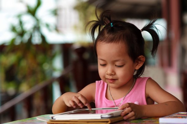 快乐的孩子盯着平板电脑。图片下载