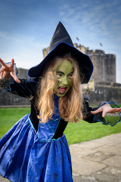 女孩装扮成女巫的绿脸和城堡的背景图片下载