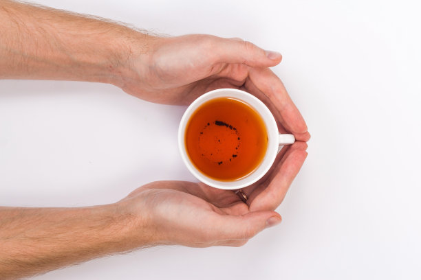 两个男人的手拿着一个茶杯。图片下载