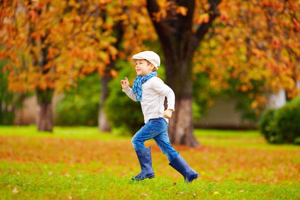 快乐的男孩在秋天的公园里跑步图片下载