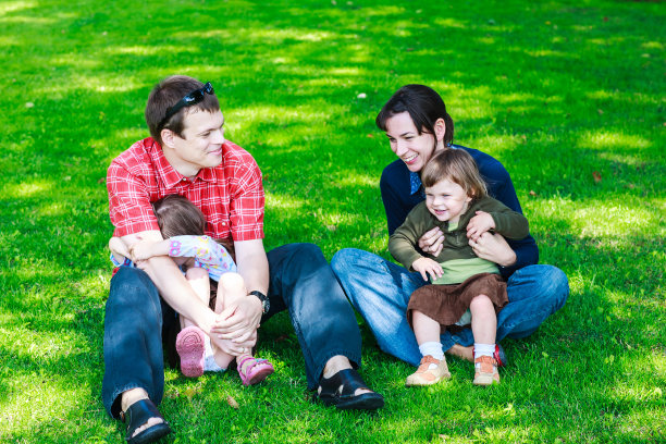 快乐的四口之家坐在草地上图片下载