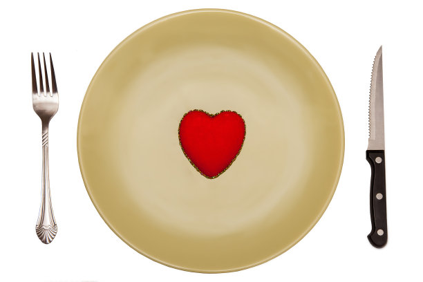 红色玩具心形与餐具置于绿色盘子上图片下载