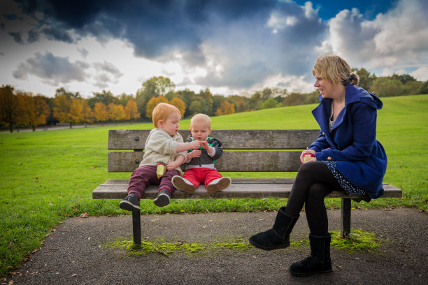 妈妈和蹒跚学步的孩子在公园长椅上分享糖果图片下载