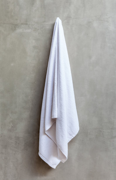 白毛巾挂在裸露的混凝土墙上。图片下载