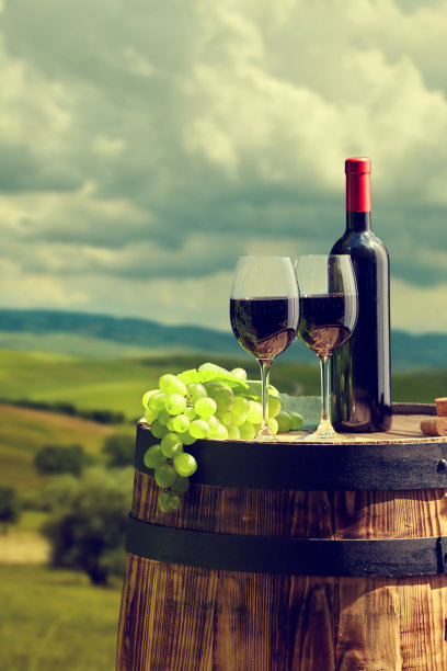 旧酒桶上的红酒酒瓶和酒杯。图片下载