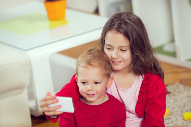 快乐的哥哥和妹妹用电话拍照图片下载