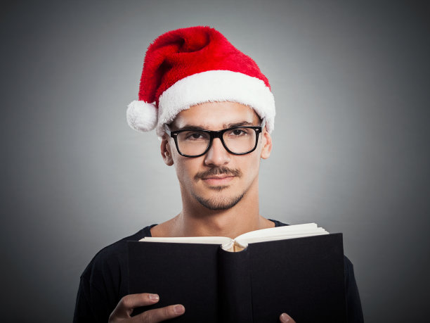 戴着圣诞老人帽子读书的年轻人图片下载
