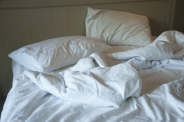 酒店里未整理的床，温暖的光线图片下载