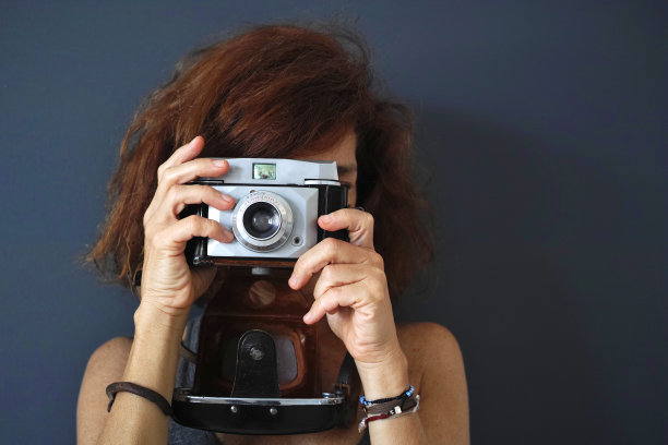 女性摄影师与老相机黑暗的背景图片下载
