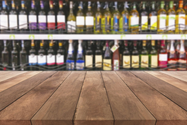 木质桌子和酒架子上的酒瓶模糊的背景图片下载