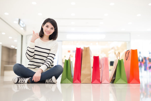 快乐的女人坐着展示购物袋素材图片