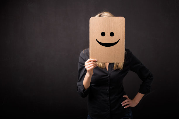 一个女人拿着一张画着笑脸的纸板图片下载