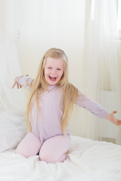 累了可爱的小女孩在床上伸懒腰图片下载