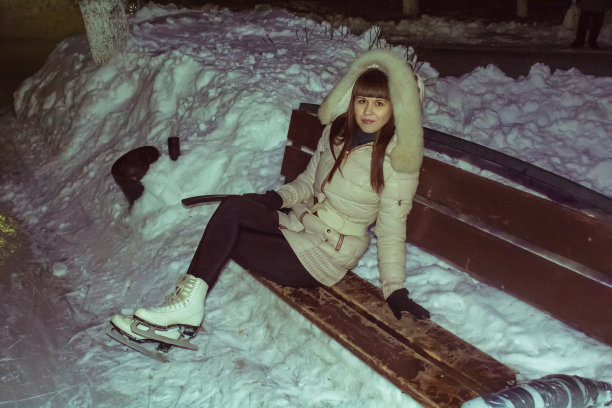 穿着冰鞋的年轻女孩坐在长凳上。图片下载