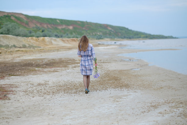 一个年轻的白人女人在海滩上散步图片下载