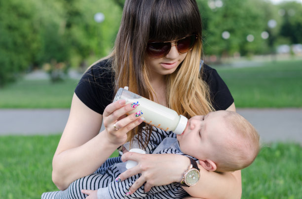 年轻的母亲在公园里喂婴儿图片下载