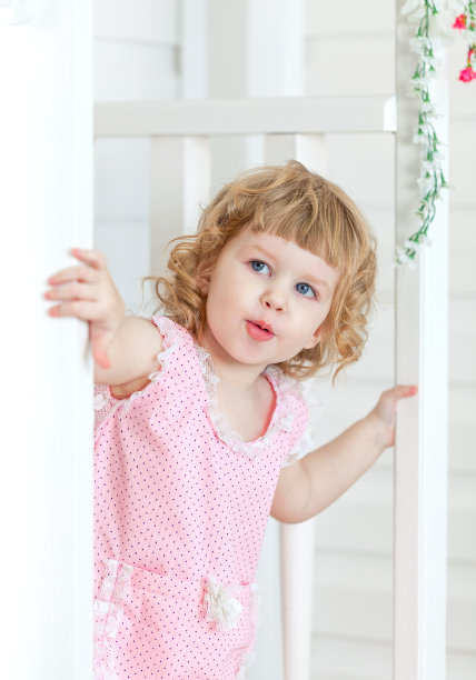 穿粉红色衣服的可爱小女孩从门后看图片下载