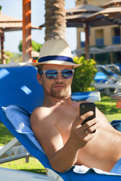 一名年轻人在游泳池里用智能手机脚发短信图片下载