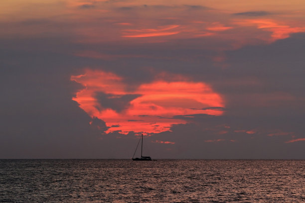 日落照片，船的剪影漂浮在天际线图片下载